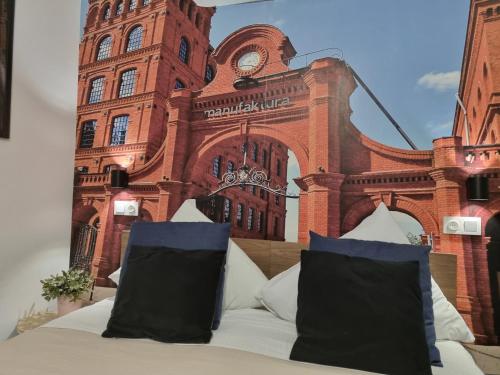 a large bed in front of a building with a clock tower at Q Apart Meta -1, 2 lub 3-pokojowe, klimatyzowane apartamenty przy Manufakturze z garażem lub parkingiem Gratis, FV in Łódź