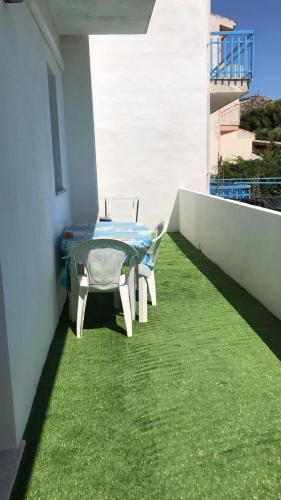 a table and a chair on a balcony with grass at Luscofusco in La Caletta