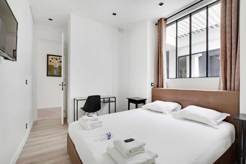 une chambre avec un lit avec des draps blancs et une fenêtre dans l'établissement Superb apartment with hammam -4BR-12P- Bastille, à Paris
