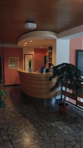 a wooden bar in a lobby with a palm tree at Hotel Rozvoj in Klatovy