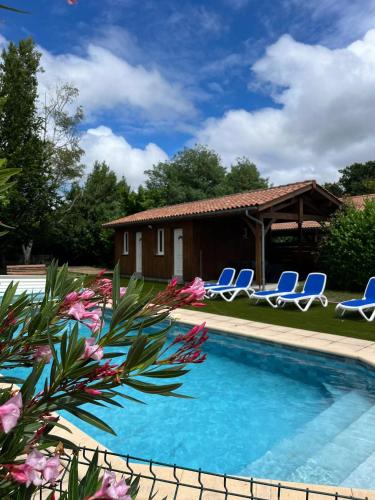une piscine avec des chaises et une maison dans l'établissement Villa spacieuse à Sainte-Eulalie-en-Born, terrasse, piscine privée, à Sainte-Eulalie-en-Born