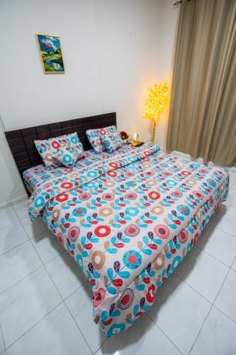 a large bed with a colorful comforter and pillows at BAITH AL JANNAH LLC Vacation home Rentals in Abu Dhabi