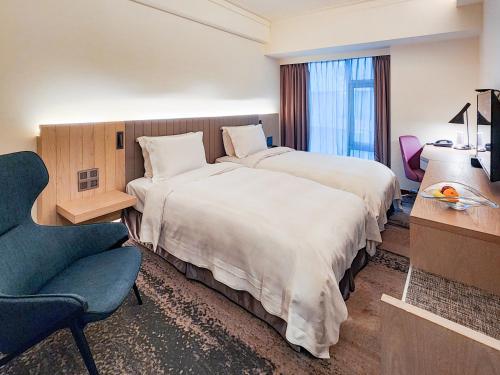 a hotel room with two beds and a chair at Howard Plaza Hotel Hsinchu in Hsinchu City
