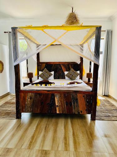 a wooden bed with a canopy in a room at Z-Breeze Zanzibar in Kiwengwa