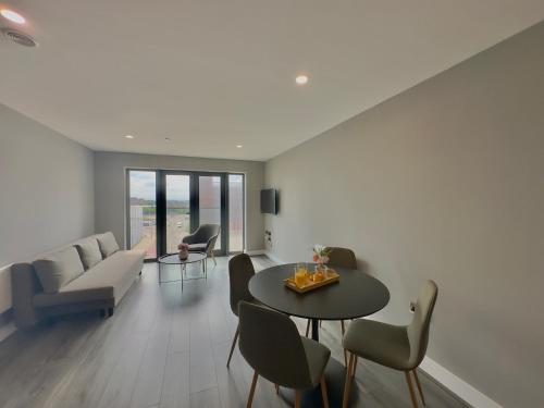 a living room with a couch and a table and chairs at Monarchs Quay Arena Apartments by Happy Days in Liverpool