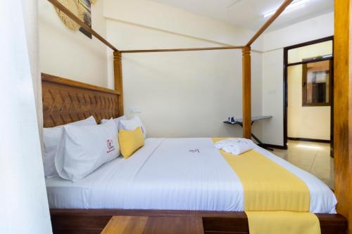 a bedroom with a large white bed with yellow pillows at ZaNaKri Homes ;A Great Panorama of Indian Ocean in Mombasa