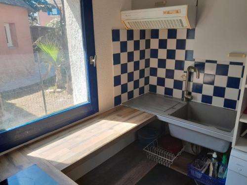une petite cuisine avec un évier et une fenêtre dans l'établissement Mas sympathique entre étang et mer !, au Barcarès