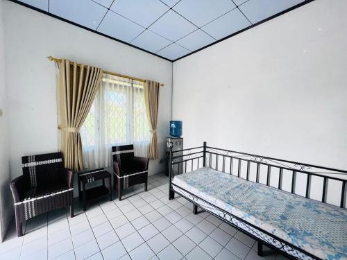 una camera da letto con un letto e due sedie di Sewa Villa Puncak Gendis a Cipanas
