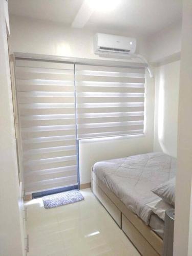 a bedroom with a bed and a window with a fan at SMDC Style Residences Condo Unit in Iloilo City