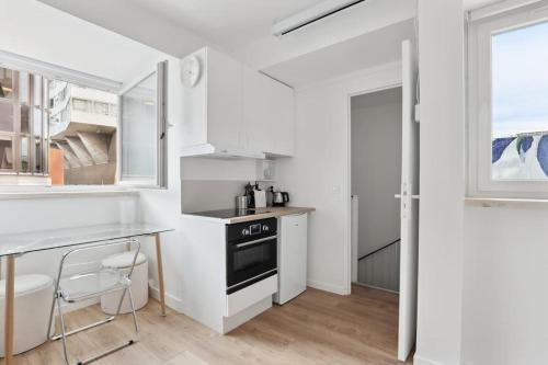 - une cuisine blanche avec une table et une cuisinière dans l'établissement ID 412 - Cozy studio Near Eifel Tower, à Paris