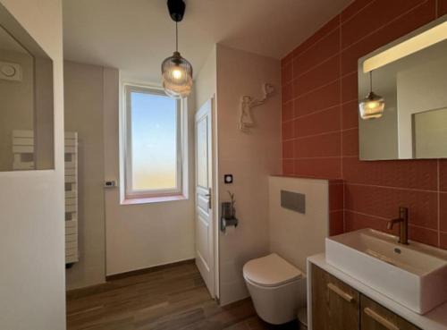une salle de bain avec un lavabo et des toilettes et une fenêtre dans l'établissement Le Family Pop-Art, à Montaigu-le-Blin