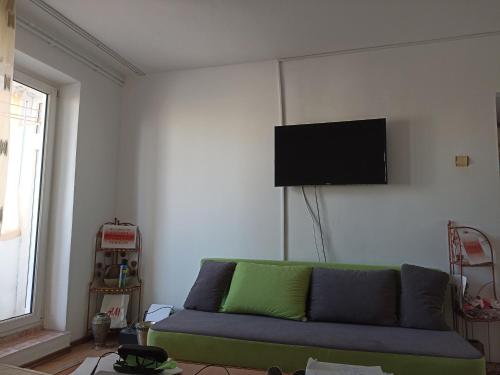 sala de estar con sofá verde y TV de pantalla plana en Apartament 3 cam Portul Turistic Mangalia, en Mangalia