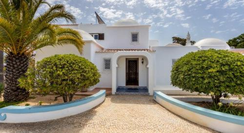 a white house with a palm tree in front of it at Casa Cinco Cupulas in Armação de Pêra