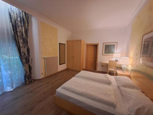 a bedroom with a bed and a desk and a window at Business Resort Parkhotel Werth in Bolzano