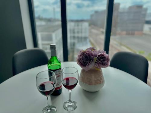 a table with two glasses of wine and a vase with flowers at Monarchs Quay Arena Apartments by Happy Days in Liverpool