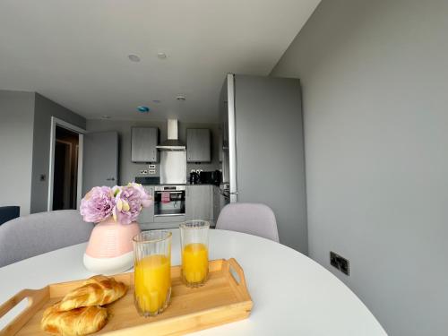 a table with two glasses of orange juice and croissants at Monarchs Quay Arena Apartments by Happy Days in Liverpool