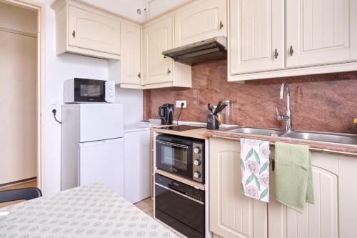 une cuisine avec des armoires blanches et un évier dans l'établissement Cosy T1 with garage near CDG | By Airnest, au Blanc-Mesnil