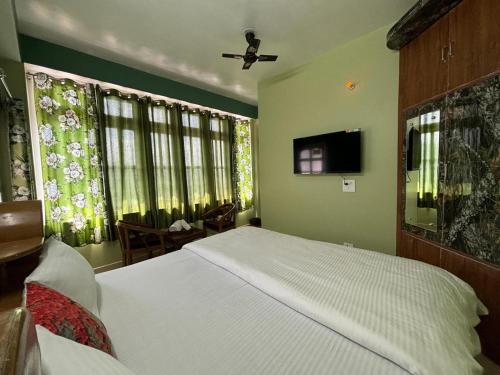 a bedroom with a bed and a flat screen tv at ZuZu - A Travellers Hostel in Shimla