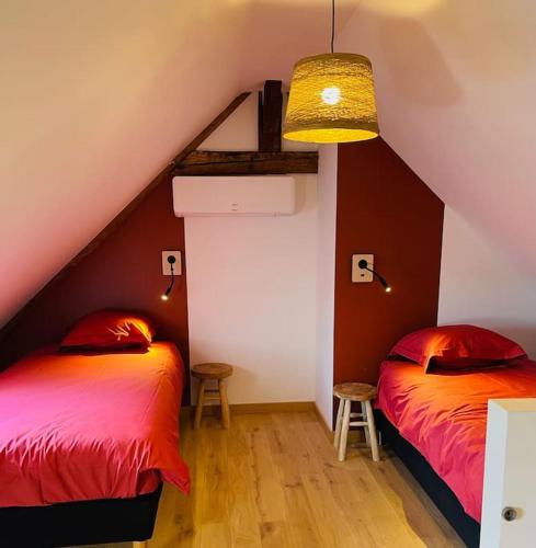 Cette chambre mansardée comprend 2 lits et des murs rouges. dans l'établissement Le chalet des bons vivants, à Montaigu-le-Blin