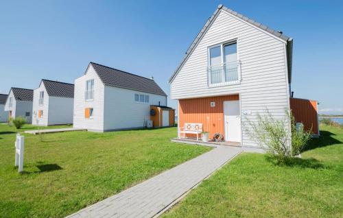 a white house with a orange door and a yard at Vogelvilla in Olpenitz