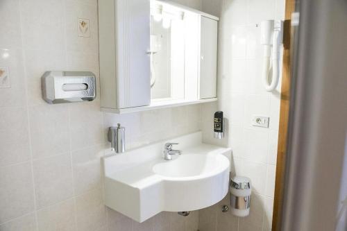 a white bathroom with a sink and a mirror at Hotel Eden in Toscolano Maderno