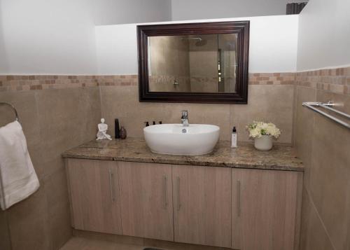 a bathroom with a white sink and a mirror at Seemeeu, Gouritsmond in Gouritzmond