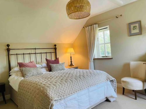 a bedroom with a bed and a chair and a window at Lower South Hill A Special Country House Near The Sea in Talbenny