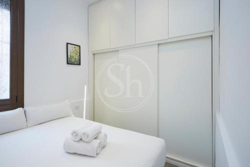 a bedroom with a white bed with towels on it at Casa tranquila cerca de Barcelona in Hospitalet de Llobregat