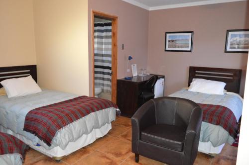 a hotel room with two beds and a chair at Hotel Cumbres de Atacama in Copiapó