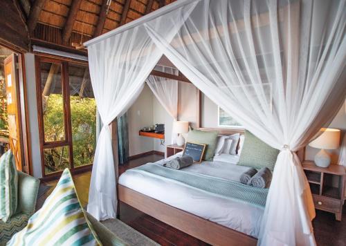 a bedroom with a canopy bed with curtains at Malkoha Lake St Lucia in Hluhluwe