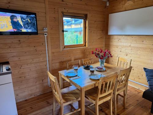 a dining room with a table and chairs and a screen at Domki Pajka in Międzyzdroje