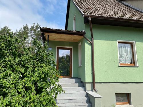 a green house with stairs leading to a door at Ferienhaus Family and Friends am Knappensee in Knappenrode