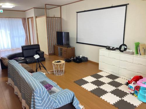 a living room with a couch and a projection screen at 寺田旅館一軒家レンタル素泊まり最大15人宿泊可能 4名様まで同一料金 in Mine