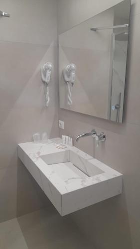 a white bathroom with a sink and a mirror at Hotel Della Valle in Agrigento