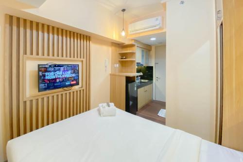 RawalembangにあるGood and Simply Studio Tokyo Riverside PIK 2 Apartment By Travelioのベッドルーム1室(白いベッド1台、壁にテレビ付)