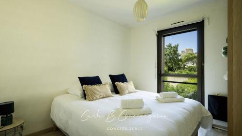 une chambre avec un grand lit blanc avec une fenêtre dans l'établissement BRISE MARINE APPARTEMENT 4 Pers FACE MER CONCARNEAU, à Concarneau