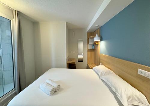 TregueuxにあるKyriad DIRECT Saint Brieuc - Parc des Expositionsのベッドとタオル2枚のある寝室