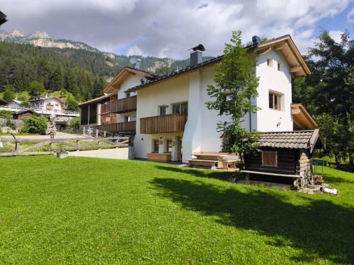 una casa bianca con un prato verde davanti di Ciasa Marta a Vigo di Fassa