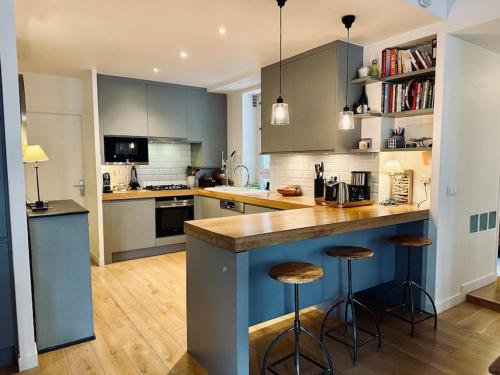 une cuisine avec des placards bleus et des tabourets de bar dans l'établissement Cosy Chic Family Flat in Paris, à Paris