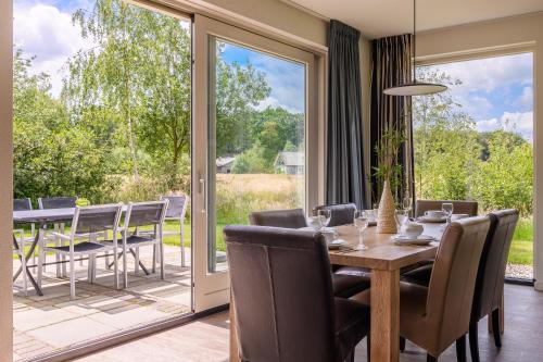 a dining room with a table and chairs and a patio at Summio Buitenplaats de Marke van Ruinen in Ruinen