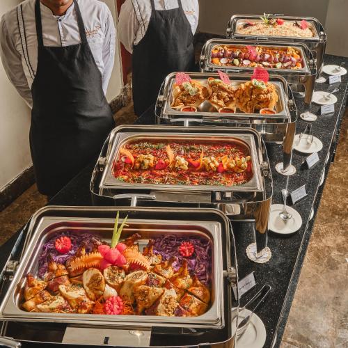 a buffet line with trays of food on a table at Triumph White Sands Hotel in Marsa Matruh