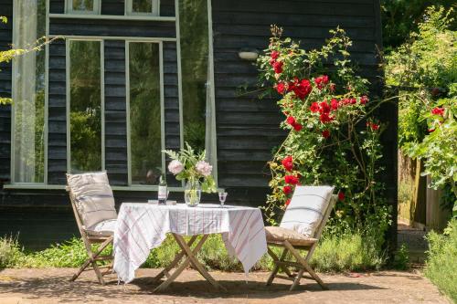 a table and chairs with a table and flowers at Deepwell Granary is a lovely thatched barn with attached meadow woodland in Buxhall
