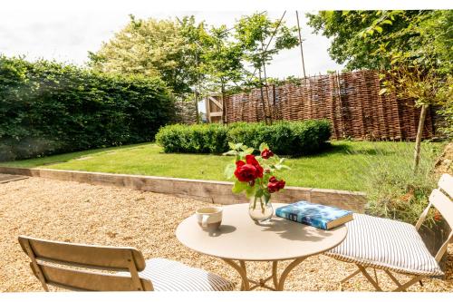 a table with a vase of flowers on it at Deepwell Granary is a lovely thatched barn with attached meadow woodland in Buxhall