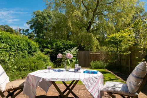 a table with a vase of flowers and two chairs at Deepwell Granary is a lovely thatched barn with attached meadow woodland in Buxhall