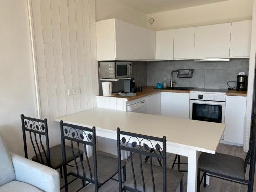 - une cuisine avec un comptoir blanc et 2 chaises dans l'établissement Appartement Résidence Héliotel, à Saint-Laurent-du-Var