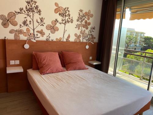 - une chambre dotée d'un lit avec des draps blancs et des papillons sur le mur dans l'établissement Appartement Résidence Héliotel, à Saint-Laurent-du-Var