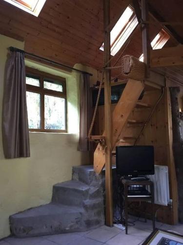 a room with stairs and a television in a house at Traditional 18th century converted stables in Wexford