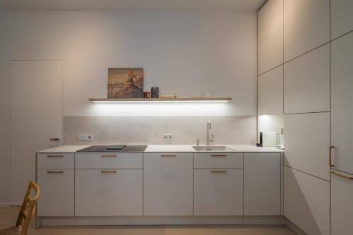 a kitchen with white cabinets and a sink at 50 meters to the Sea in Juodkrantė