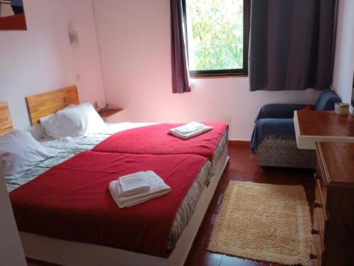 a bedroom with a red bed with two towels on it at Apartamento Almargem in Conceição