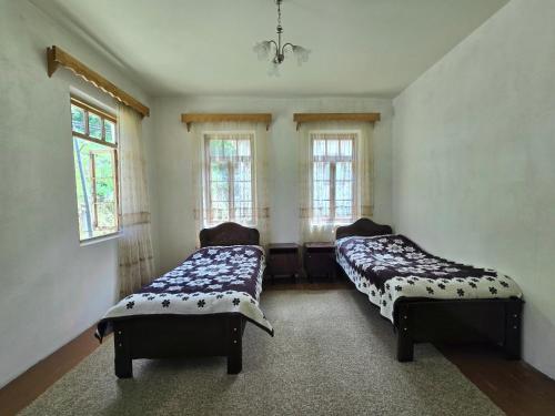 two beds sitting in a room with windows at Guesthouse Mareti in Shuakhevi